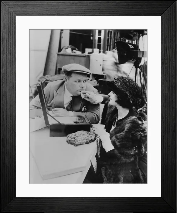 Framed Print : Roscoe Fatty Arbuckle, American actor, getting touch up by make up girl on movie set, c. 1920. Arbuckle was one of the most popular silent stars of the 1910s