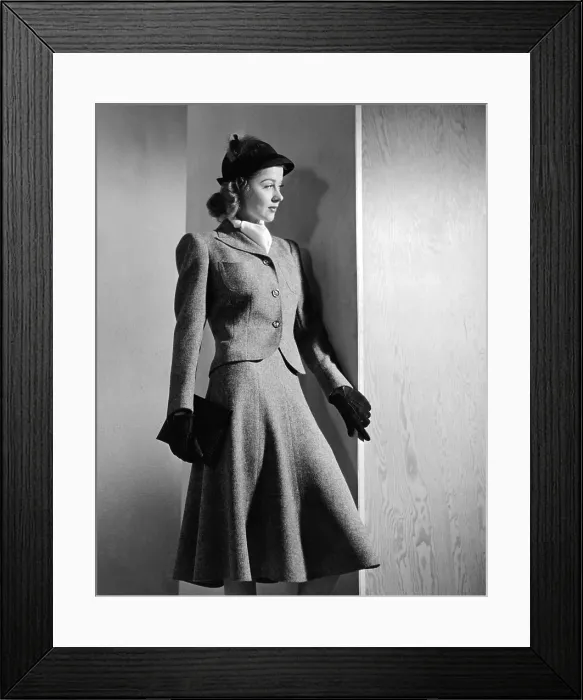 Framed Print : Woman's suit with a short narrow waisted jacket and emphatically padded shoulders