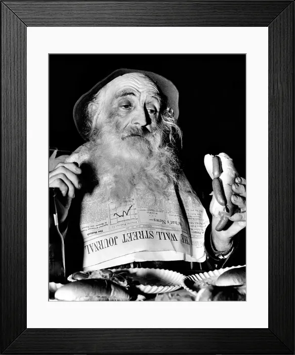 Framed Print : A homeless man, enjoys a free lunch at the Bowery Follies in New York. He uses the Wall Street Journal as a bib while enjoying free beer and hotdogs. May 18, 1961