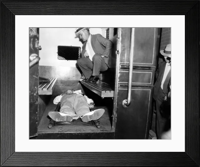 Framed Print : John Dillinger, dead with toes up in a police patrol wagon, is taken from the scene of his killing by FBI agents in Chicago. July 22, 1934