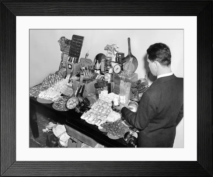 Framed Print : Evidence gathered in arrest of counterfeiters included $10, 000 in bogus coins. Secret Service agent looks over the haul. Jan. 31, 1942
