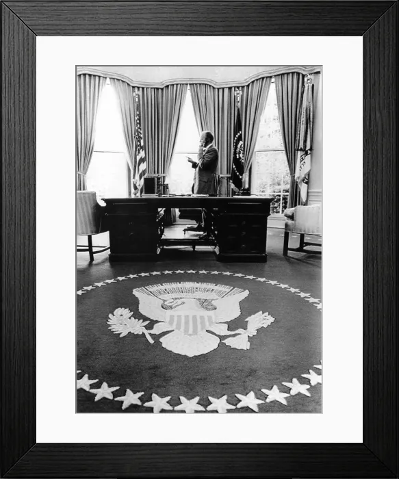 Framed Print : President Gerald Ford's first week in office. With Presidential seal carpet in the foreground, Ford stands during a telephone conversation in the Oval Office. Aug. 18, 1974