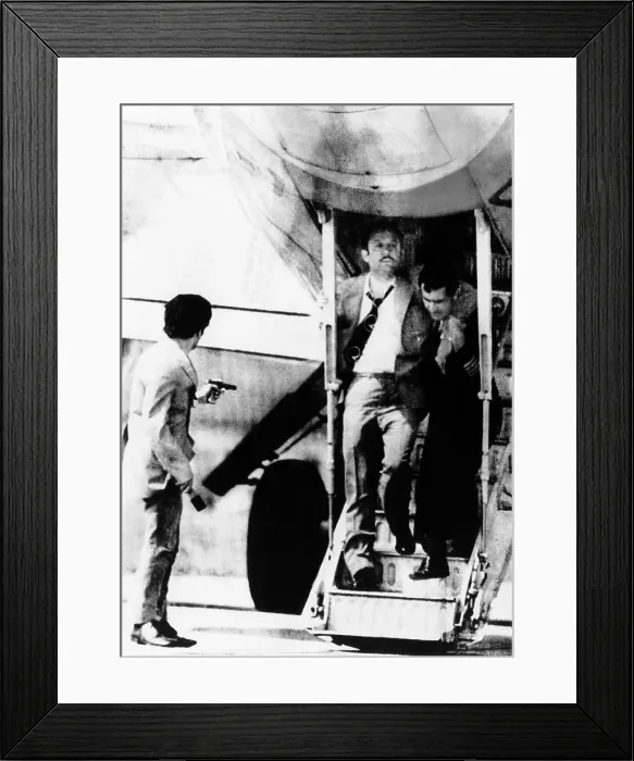 Framed Print : An armed hijacker (left) watches as Turkish Airlines crew member employee assists a passenger who suffered a heart attack on the air liner at Sofia, Bulgaria