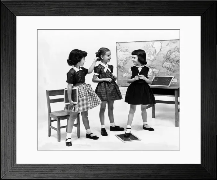 Framed Print : Little girls school dressed in 1953. They echo the Dior's New Look with their full gathered skirts and belted waists, worn with crisp white ankle socks