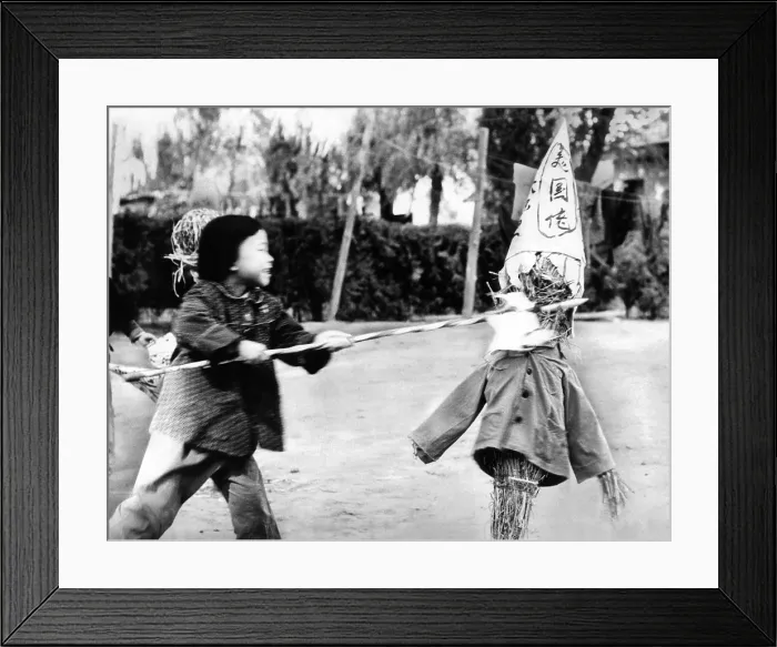 Framed Print : A Chinese kindergarten girl thrusts a spear into a straw effigy labeled with a sign, which roughly translated reads US bad guys