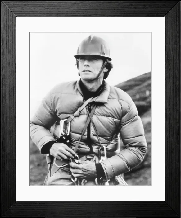 Framed Print : THE EIGER SANCTION, Clint Eastwood straps on equipment for a day's filming on the north face of Switzerland's Eiger Mountain, 1975