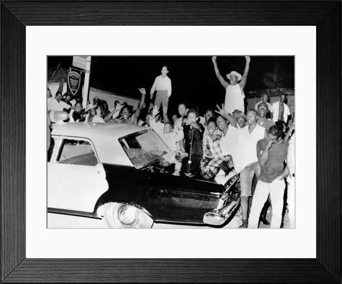 Framed Print : African American jeer police during the 1965 Watts Riots. Young men stand on a Police car on the second night of the violence protests. August 12, 1965