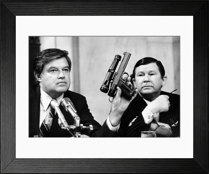 Framed Print : Senator Frank Church was chairman of the Senate Intelligence Committee. As John Tower looks on, he holds a CIA dart gun with a telescopic site