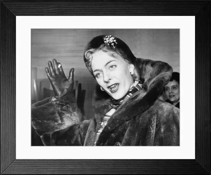 Framed Print : Christine Jorgensen, waves to photographers, upon her arrival at Idlewild from Denmark. Feb. 12, 1953