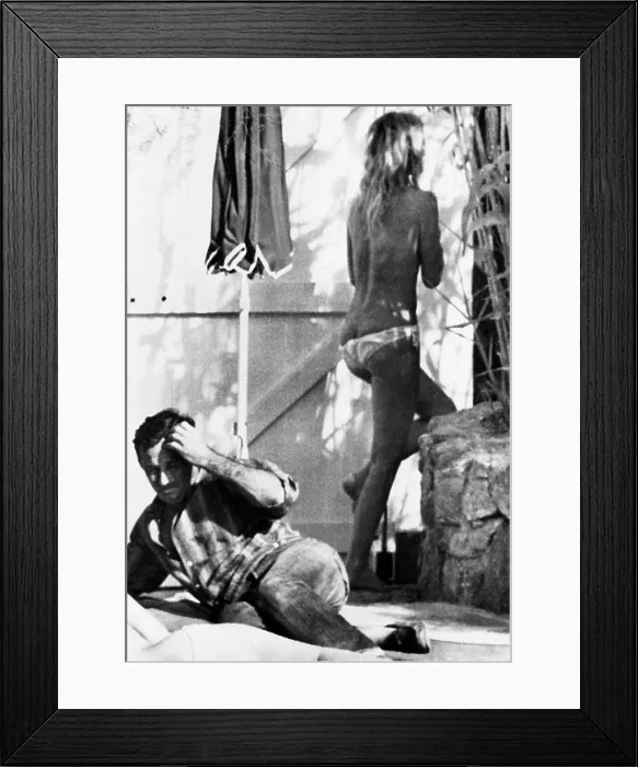 Framed Print : Brigitte Bardot retreats indoors when she spots a photographer taking pictures of her home. She was sunbathing topless with friends in St. Tropez, France