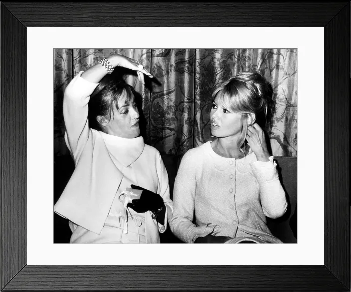 Framed Print : French actresses Jean Moreau (left) and Brigitte Bardot chat as they wait for a flight to Paris