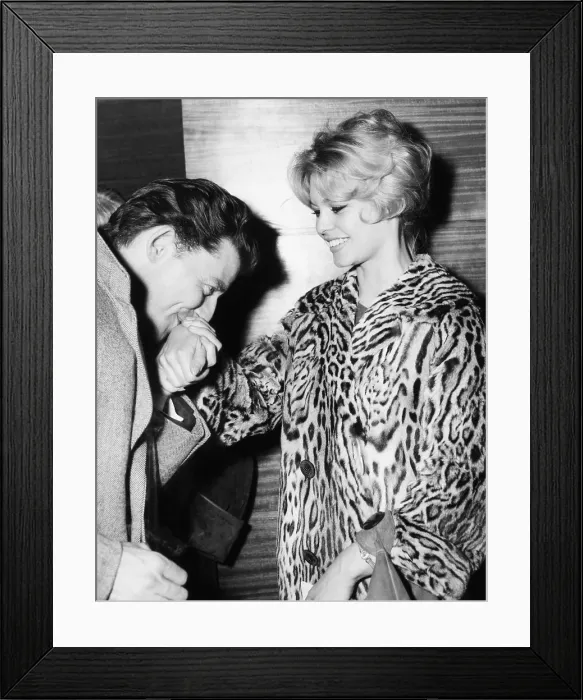Framed Print : Brigitte Bardot receives an old-fashioned style kiss from actor Gerald Philippe. They were attending the premiere of the movie Montparnasse 19 in Paris