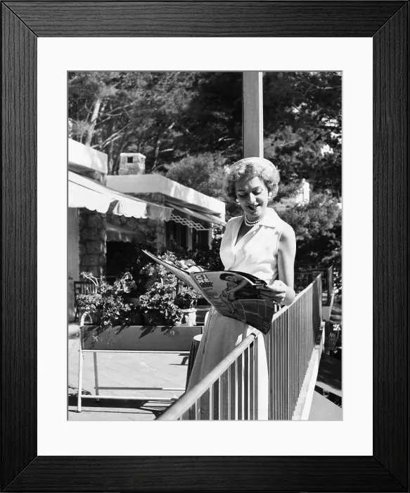 Framed Print : Christine Jorgensen, leafing through a film magazine on Capri, Italy, Sept. 22, 1954 Framed Print : Christine Jorgensen, leafing through a film magazine on Capri, Italy, Sept. 22, 1954