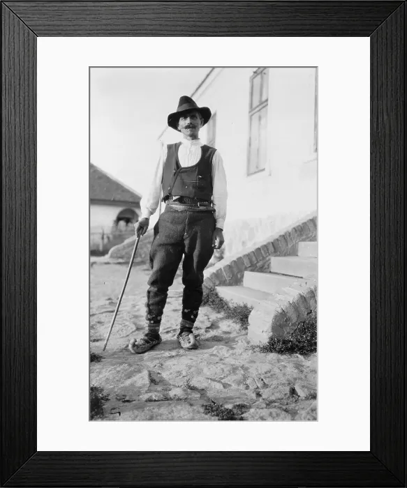 Framed Print : Serbian man wearing hat, vest, belted pants and pointed shoes with cane standing outside of building in Yugoslavia, circa 1880-1924