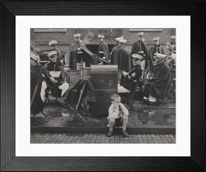 Framed Print : Watching for the parade, child seated on a curb with a military band behind, photograph by Louise Rosskam, North Street, Washington DC, 1938
