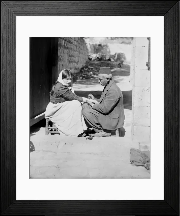 Framed Print : Woman being tattooed by a man in a fez, original caption: Tattoing a pilgrim, Jerusalem, American Colony Photo Department, 1900-1920