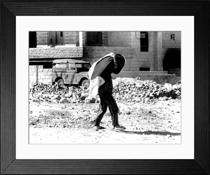 Framed Print : Arab-Israeli War, Jordanian in pajamas (carrying mattress & blankets) walking through war-torn city of Amman, Jordan, September 26, 1970