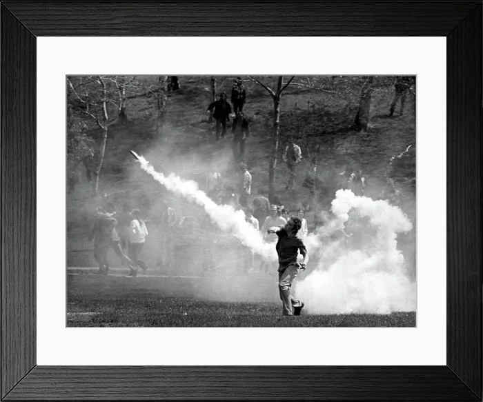 Framed Print : KENT STATE UNIVERSITY, student tosses a tear-gas bomb back at the National Guard who fired it to disperse the crowd. Kent, Ohion 5 / 4 / 70