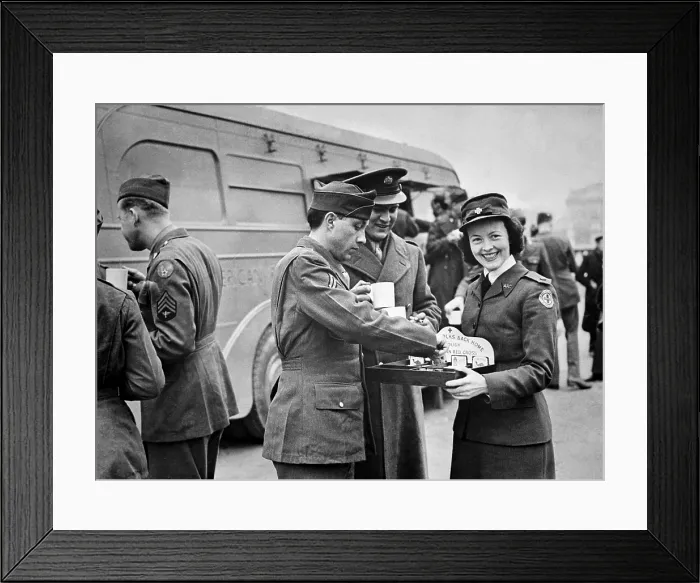 Framed Print : A Red Cross worker smiles as she offers American soldiers candy and cigarettes after the 'Wings for Victory' week celebration in London, England, March 1943