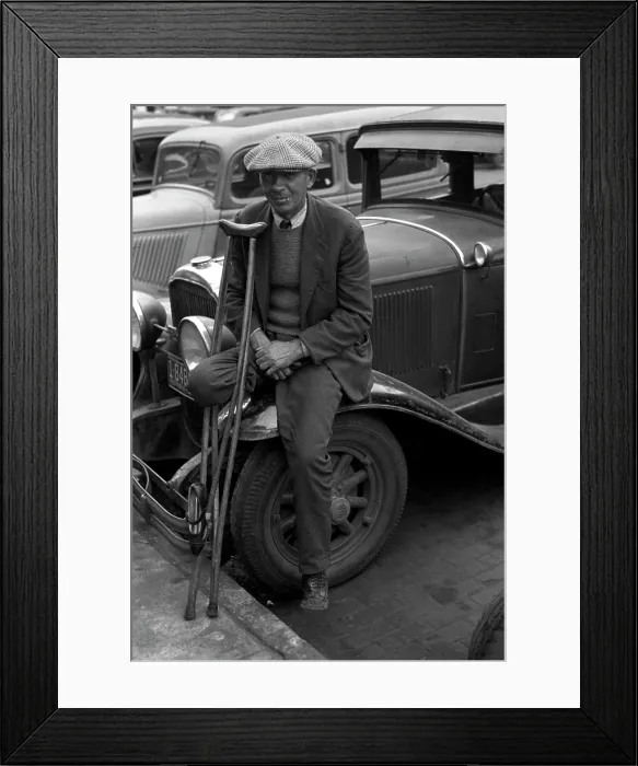 Framed Print : War veteran who sells pencils, a man with an amputated leg with crutches leaning against a car, Omaha, Nebraska, photograph by John Vachon, November, 1938
