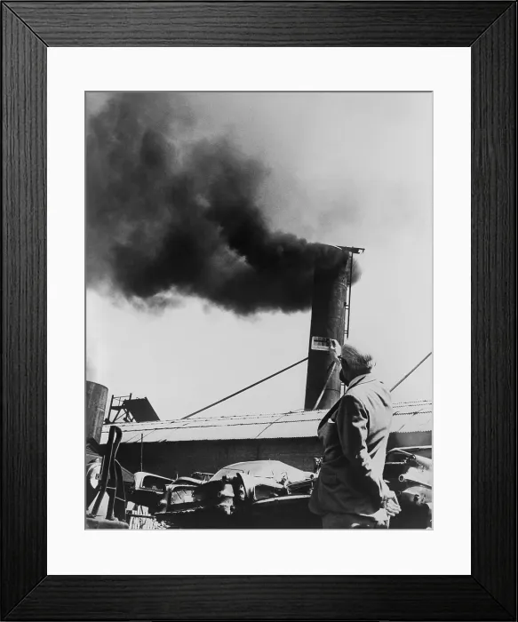 Framed Print : Air Pollution is measured by holding up card with different shades in front of smokestack, in order to identify the extent of air pollution. 1967