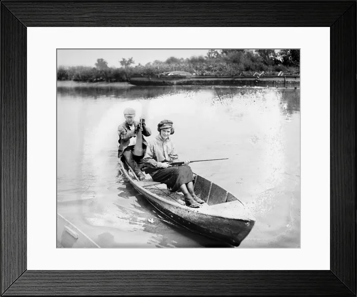 Framed Print : Man and woman in a canoe, the woman holds a gun, 1921