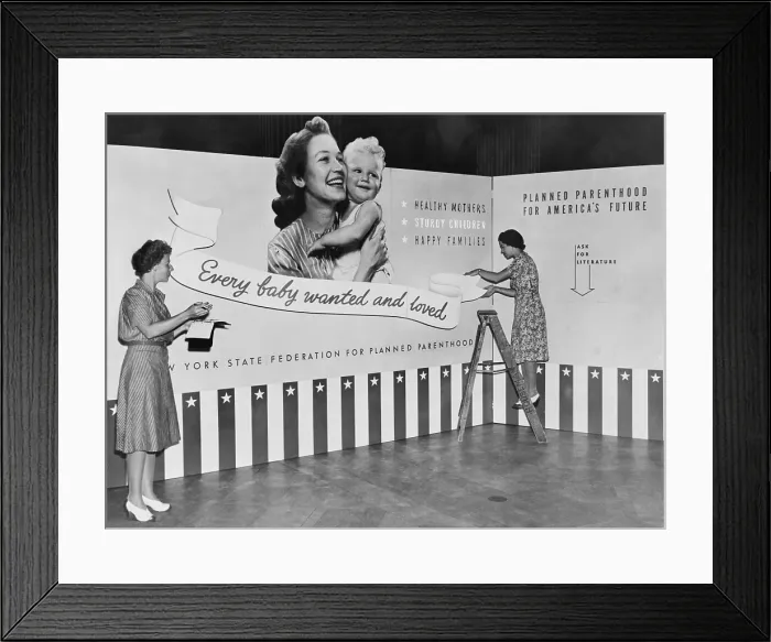 Framed Print : Two women working on panels for exhibit on planned parenthood featuring the slogan, Every baby wanted and loved