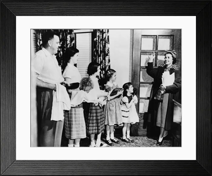 Framed Print : Mrs. E. J. Siegwarth, Jr. waving good-bye to her family as she leaves for work, while her husband and children dry the dishes