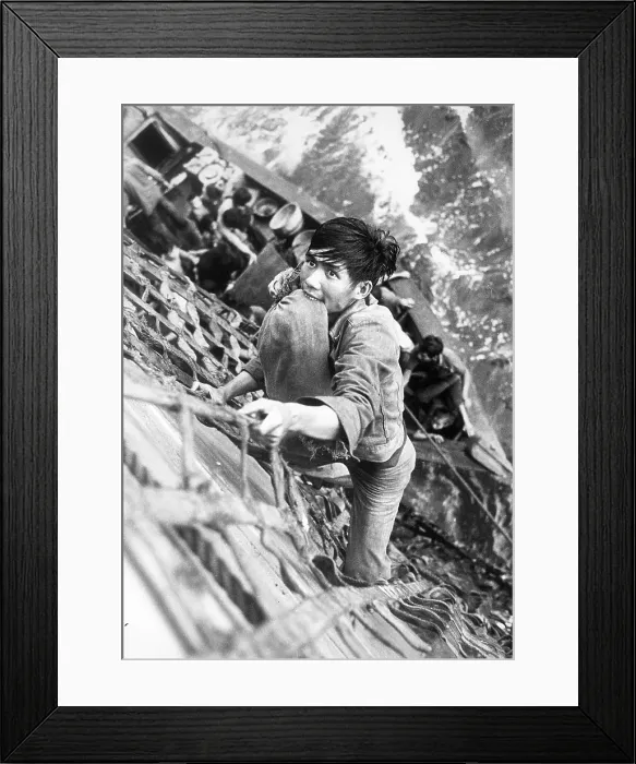 Framed Print : Vietnam War, South China Sea, a Vietnamese Refugee with his belongings secured in between his teeth, climbs a cargo net to the deck of the combat store ship USS White Plains Framed Print : Vietnam War, South China Sea, a Vietnamese Refugee with his belongings secured in between his teeth, climbs a cargo net to the deck of the combat store ship USS White Plains