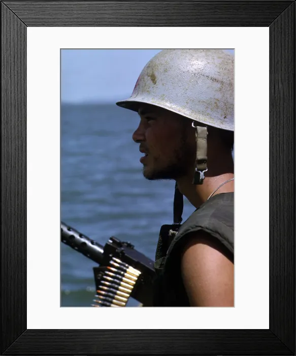 Framed Print : Vietnam War, a Navy gunner mans his 50 caliber machine gun on utility boat as it cruises in the Rung Sat zone of South Vietnam during Operation Jackstay, circa late 1960s