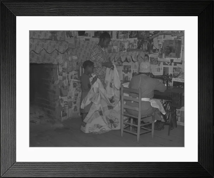 Framed Print : African American mother is assisted by her two daughters as she sews a quilt in their newspapered home on the Pettway plantation in Gees Bend, Alabama. April 1937 Framed Print : African American mother is assisted by her two daughters as she sews a quilt in their newspapered home on the Pettway plantation in Gees Bend, Alabama. April 1937