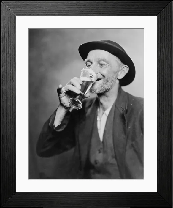 Framed Print : Happy old man drinking glass of beer, with his daintier finger extended. 1937