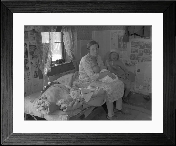 Framed Print : Mother nursing her infant on a bed with another young child, surrounded by the news papered walls of a shack in the Missouri Ozarks. Photo by Carl Mydans, June 1936