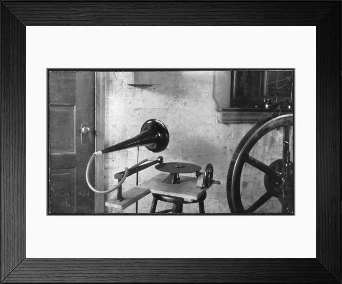 Framed Print : One of the first gramophones set next to a large mechanical wheel, by Emile Berliner, 1888