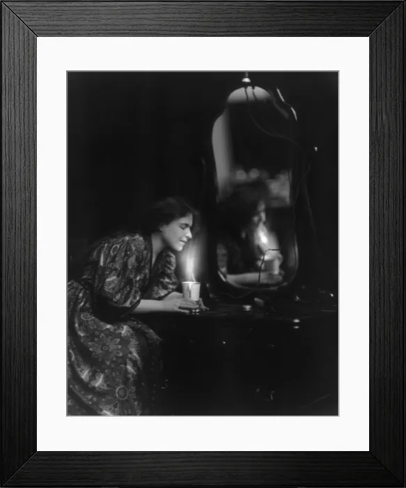 Framed Print : General Electric advertising photo of woman at dresser heating a cup of water with a General Electric appliance. Ca. 1908