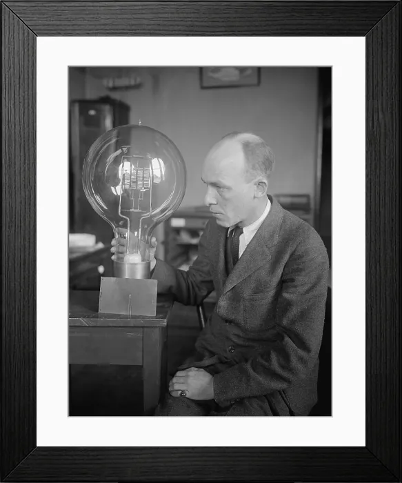Framed Print : C.W. Mitman, Head Curator, Department of Engineering and Industries of the Smithsonian Institute, holds a giant light bulb. For contrast a midget bulb is placed beside it