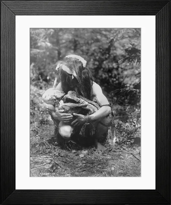 Framed Print : Kwakiutl man, crouched, cradling mummy bound in fetal position, title: Preparing to eat the mummy, photograph by Edward S. Curtis, circa 1911