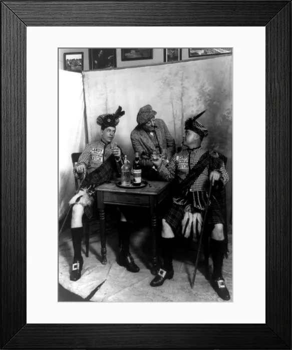 Framed Print : Two men wearing kilts seated at small table, drinking Sandy MacDonald scotch, with man standing and leaning against the table, photograph, 1913 Framed Print : Two men wearing kilts seated at small table, drinking Sandy MacDonald scotch, with man standing and leaning against the table, photograph, 1913