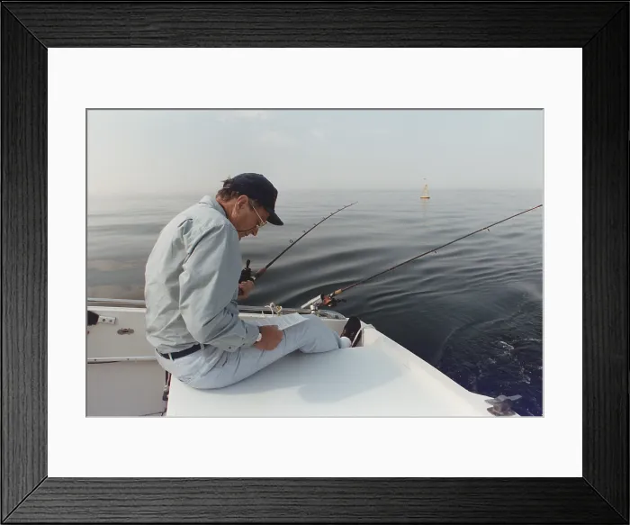 Framed Print : President George H.W. Bush reading a long memo as he fishes at his summer home in Kennebunkport Maine. Ca. 1990