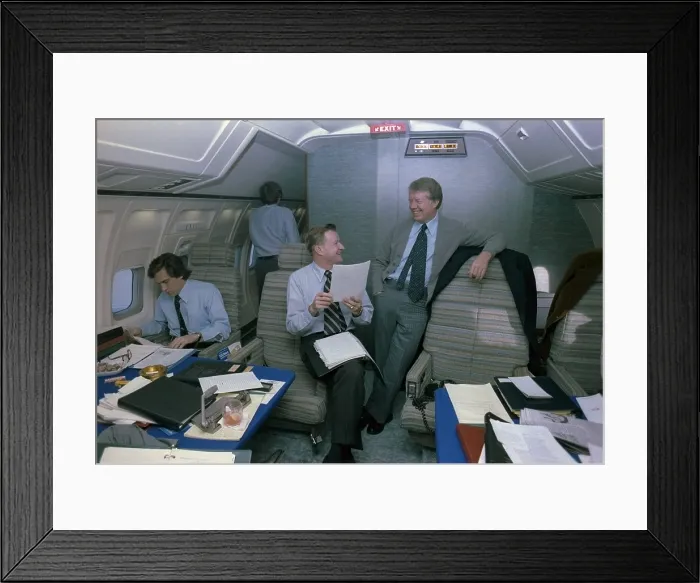 Framed Print : Zbigniew Brzezinski and Jimmy Carter in a relaxed discussion aboard Air Force One while an young staffer works in amid papers and notebooks. Ca. 1977-1980