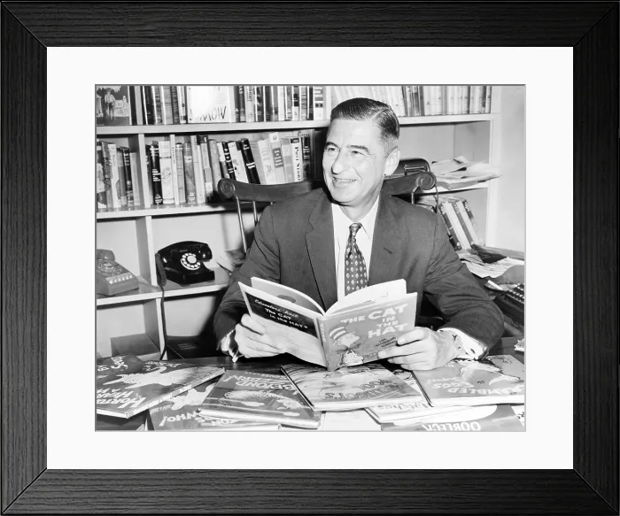Framed Print : Ted Geisel (Dr. Seuss) (1904-1991) seated at desk covered with his uniquely humorous children's books. 1957