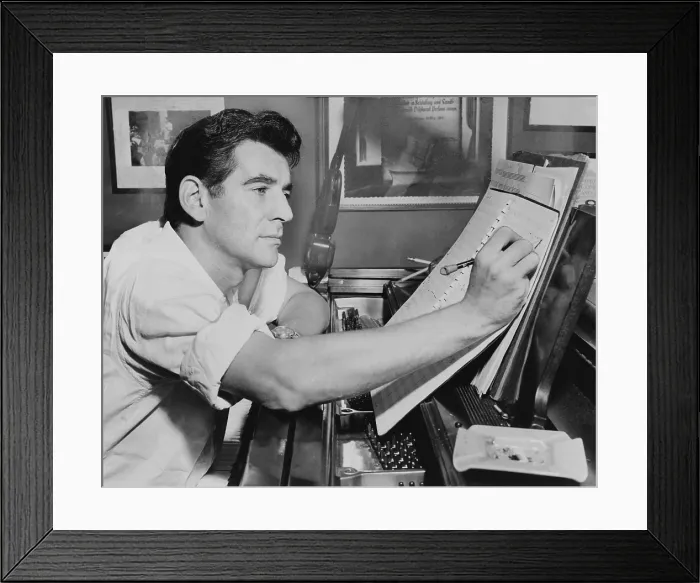 Framed Print : Leonard Bernstein (1918-1990), seated at piano, making annotations to musical score IN 1955