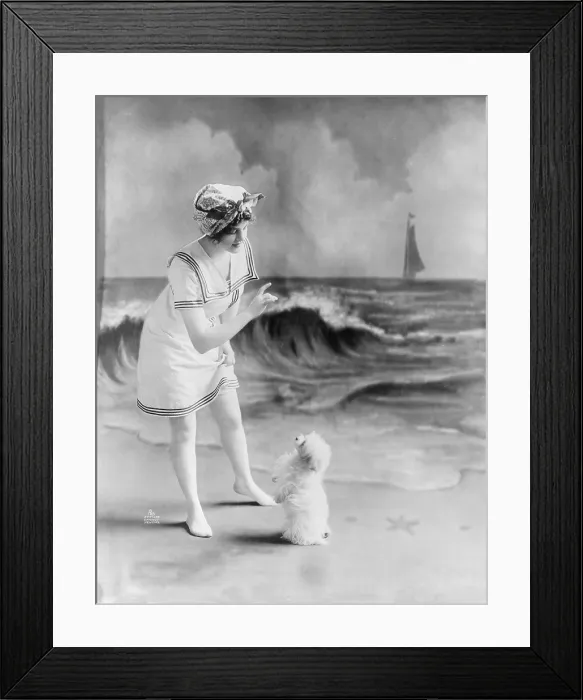 Framed Print : Bathing beauty, young woman in bathing suit with small dog in front of studio backdrop of beach, photograph, 1913 Framed Print : Bathing beauty, young woman in bathing suit with small dog in front of studio backdrop of beach, photograph, 1913