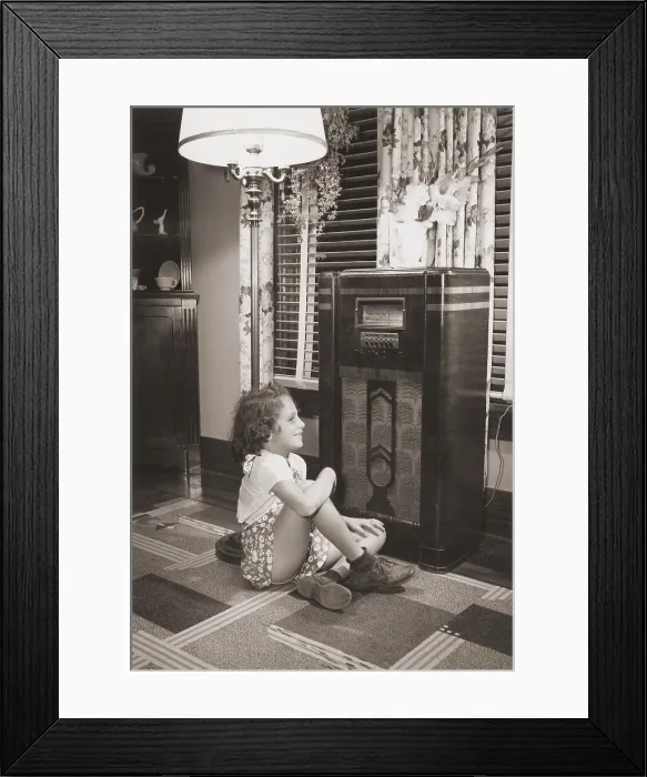 Framed Print : Little girl smiles as she enjoys a radio program in the 1930s Framed Print : Little girl smiles as she enjoys a radio program in the 1930s