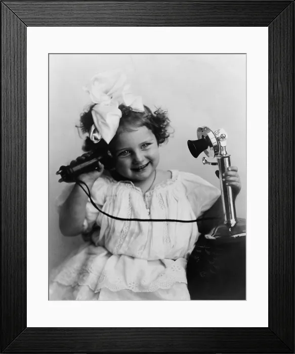 Framed Print : Little girl talking on an early model telephone. Ca. 1905 Framed Print : Little girl talking on an early model telephone. Ca. 1905