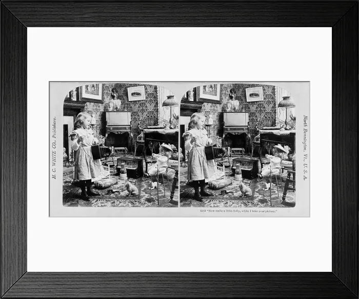 Framed Print : A young girl prepares to photograph her doll, titled: Now smile a little dolly, while I take your picture, stereo photograph by H.C. White Company, 1902 Framed Print : A young girl prepares to photograph her doll, titled: Now smile a little dolly, while I take your picture, stereo photograph by H.C. White Company, 1902