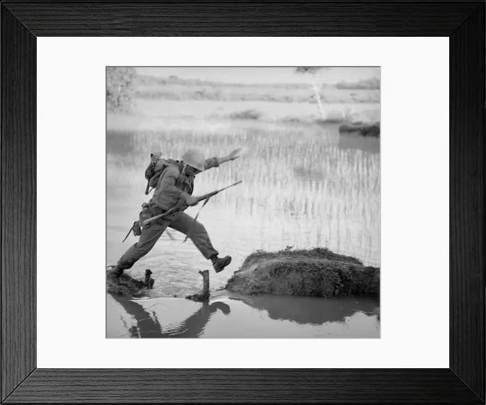 Framed Print : Vietnam War. A US Marine rifleman leaps across a break in a rice paddy dike during a search and destroy mission of Operation Colorado. Aug. 15, 1966