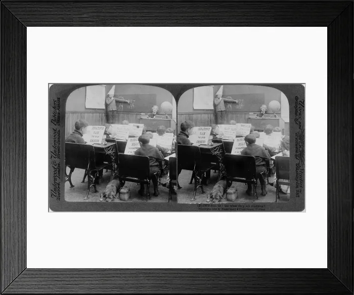 Framed Print : Classroom with children reading various crime stories and boy, wearing dunce cap, at blackboard, original title: But, Oh! see what they are studying