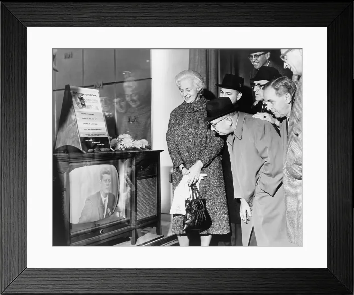 Framed Print : People gather around a television outside a store window on a New York street as President John F. Kennedy speaks during a press conference on November 21, 1962