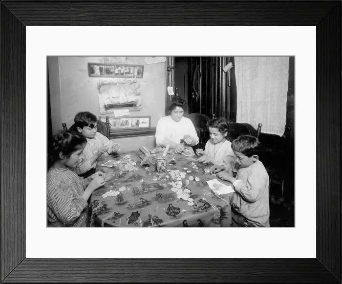 Framed Print : Woman, two boys, and two girls sitting at a table, making artificial flowers, New York City, photograph by Lewis Wickes Hine, March, 1922